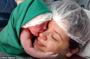 Новорожденная малышка обнимает мамино лицо