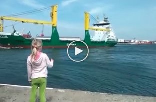 Маленькая девочка, стоящая на пристани, просит посигналить проплывающий корабль   